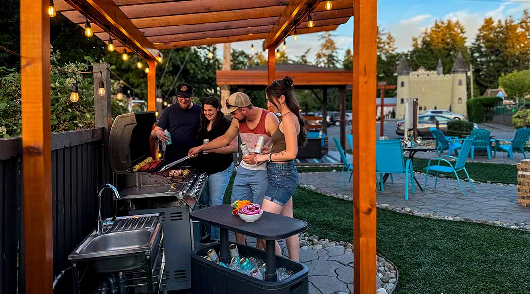 Group of people around a outdoor BBQ cooking food