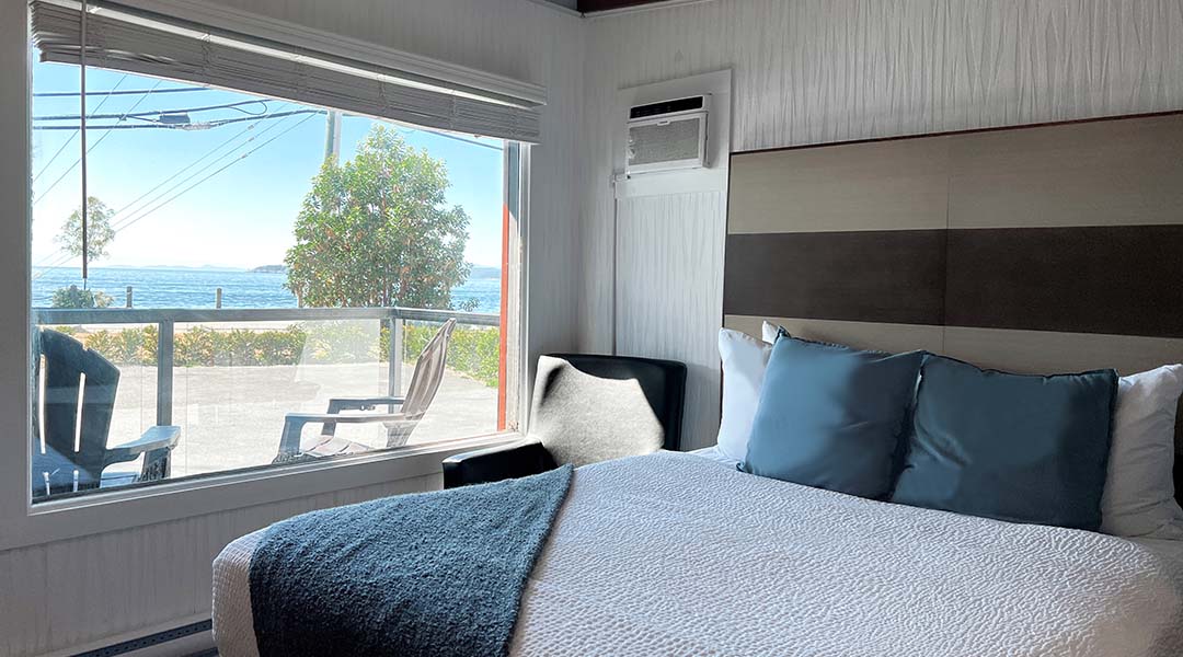 Interior of Oceanside Villas showing a bed, corner chair, and ocean views