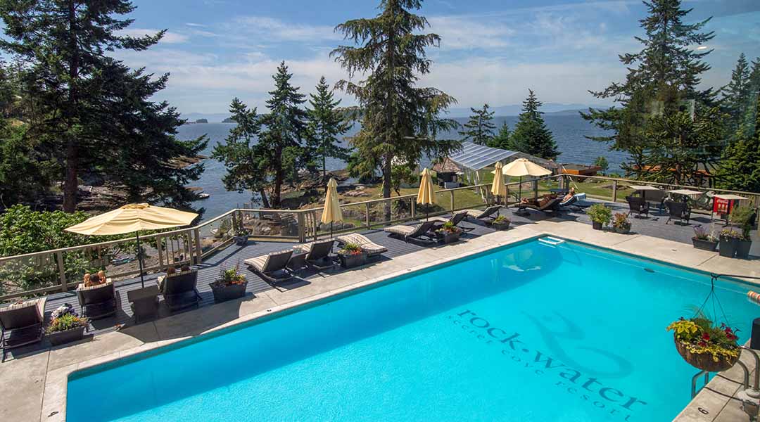 Outdoor pool at Rockwater Secret Cove Resort with lounge chairs and umbrellas
