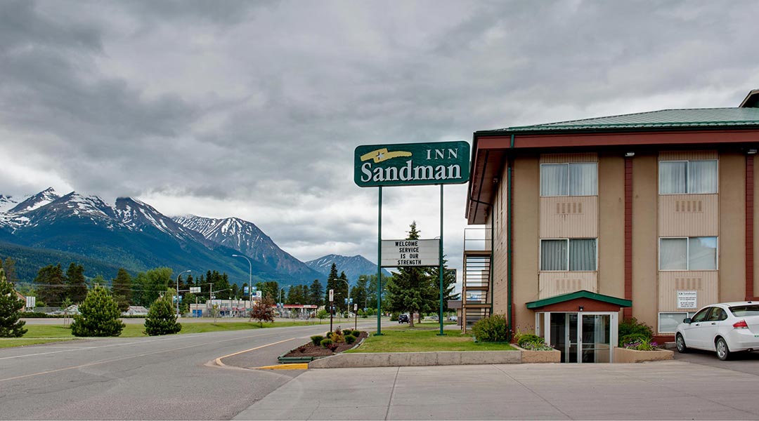 The exterior building and sign of the Sandman Inn Smithers near snowcapped mountains in Northern BC The exterior building and sign of the Sandman Inn Smithers near snowcapped mountains in Northern BC