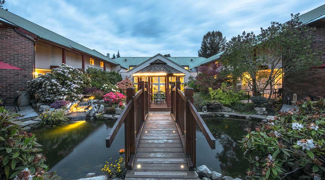 The outdoor garden with a pond and bridge leading towards the exterior of the Gibsons Garden Hotel on the Sunshine Coast The outdoor garden with a pond and bridge leading towards the exterior of the Gibsons Garden Hotel on the Sunshine Coast
