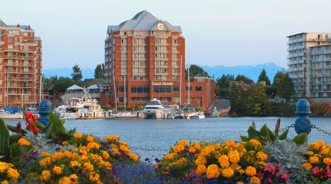 The exterior building of the Coast Victoria Hotel and Marina By APA on Vancouver Island by the ocean and harbour during spring