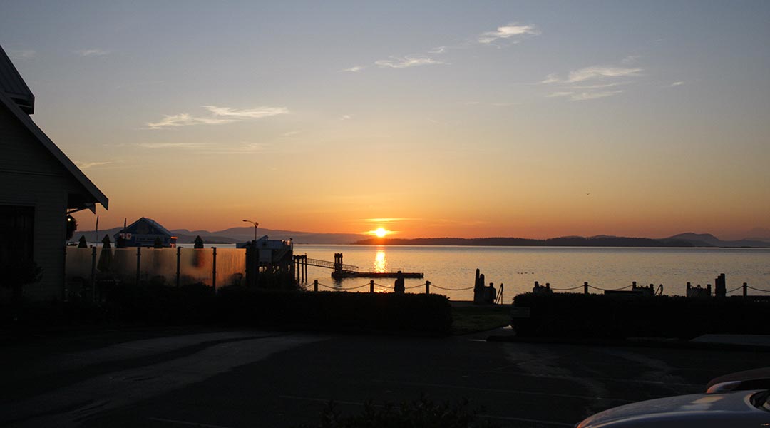 View of ocean and silhouette of buildings outside the Sidney Waterfront Inn and Suites on Vancouver Island at sunrise View of ocean and silhouette of buildings outside the Sidney Waterfront Inn and Suites on Vancouver Island at sunrise