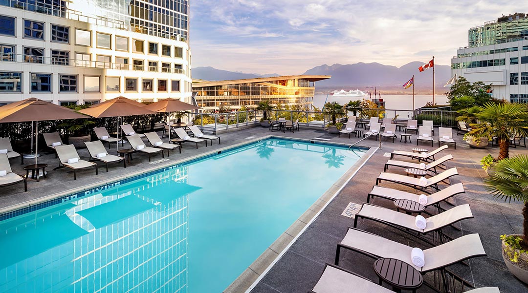 The outdoor pool area with a hrabour and mountain view at the Fairmont Waterfront in Downtown Vancouver