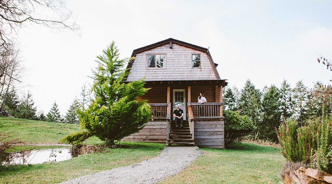 Couple relaxing on the balcony of a wooden cabin at the Bodega Ridge on Galiano Island Couple relaxing on the balcony of a wooden cabin at the Bodega Ridge on Galiano Island