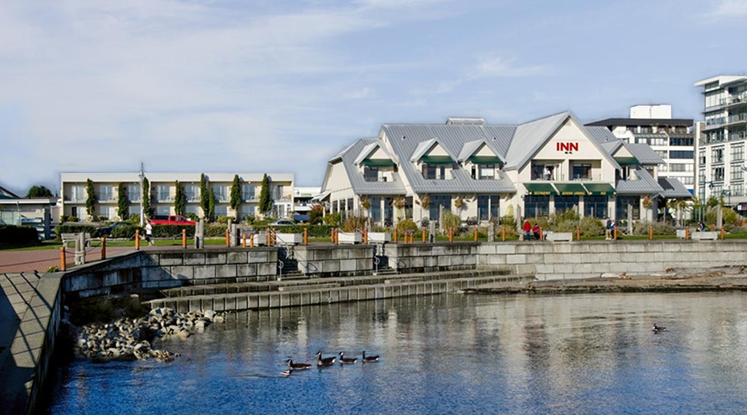The exterior building of the Sidney Waterfront Inn and Suites by the ocean water on Vancouver Island The exterior building of the Sidney Waterfront Inn and Suites by the ocean water on Vancouver Island