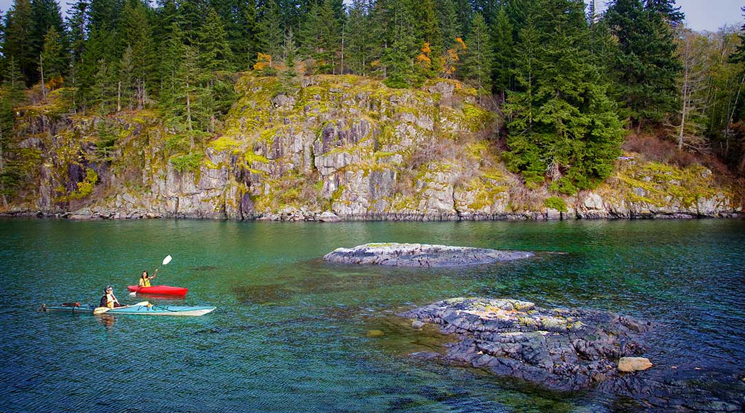 Two kayakers kayaking in the ocean nearby the Gowlland Harbour Resort on Quadra Island Two kayakers kayaking in the ocean nearby the Gowlland Harbour Resort on Quadra Island