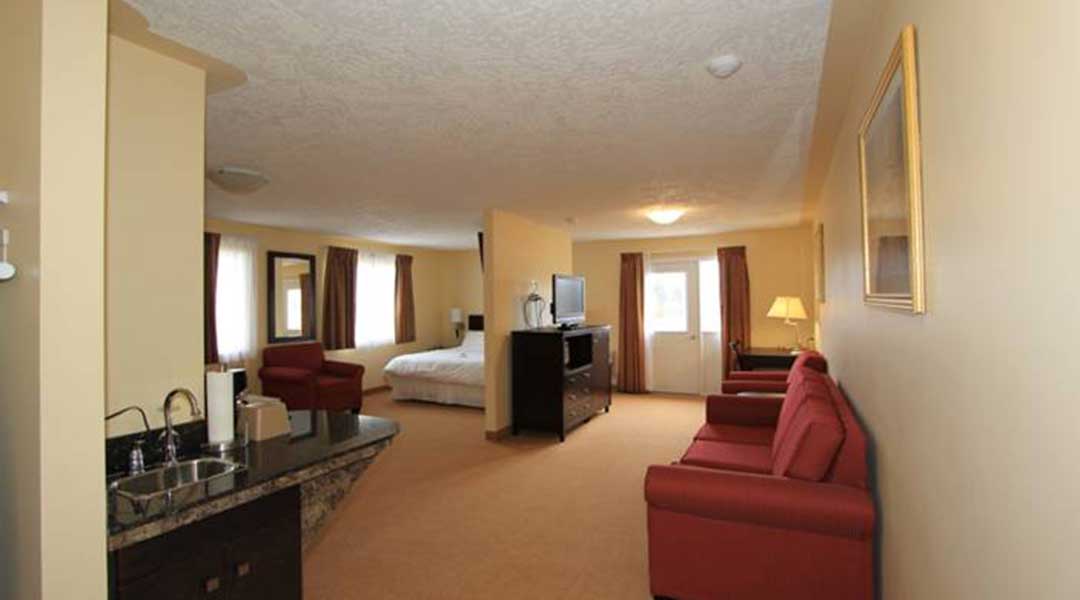 Living area and kitchenette with bed in the background in the VIP suite at Sunshine Inn in Smithers BC Living area and kitchenette with bed in the background in the VIP suite at Sunshine Inn in Smithers BC
