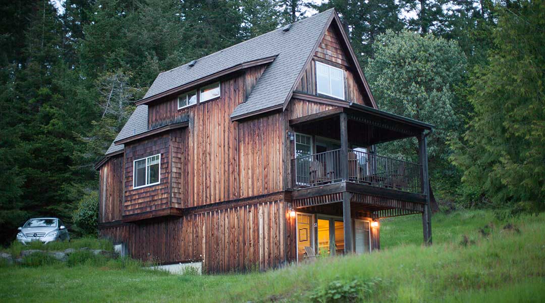 The exterior of a wooden cottage with a parked car in the evening at the Cottages on Salt Spring Island The exterior of a wooden cottage with a parked car in the evening at the Cottages on Salt Spring Island