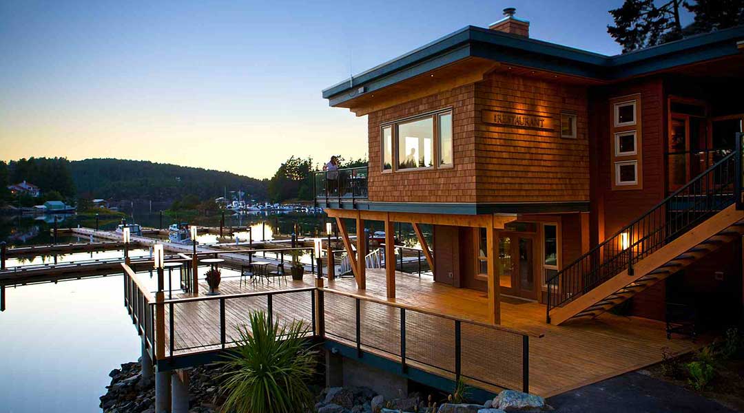 Exterior of the Painted Boat Resort Spa and Marina at sunset with ocean in background in Madeira Park Exterior of the Painted Boat Resort Spa and Marina at sunset with ocean in background in Madeira Park