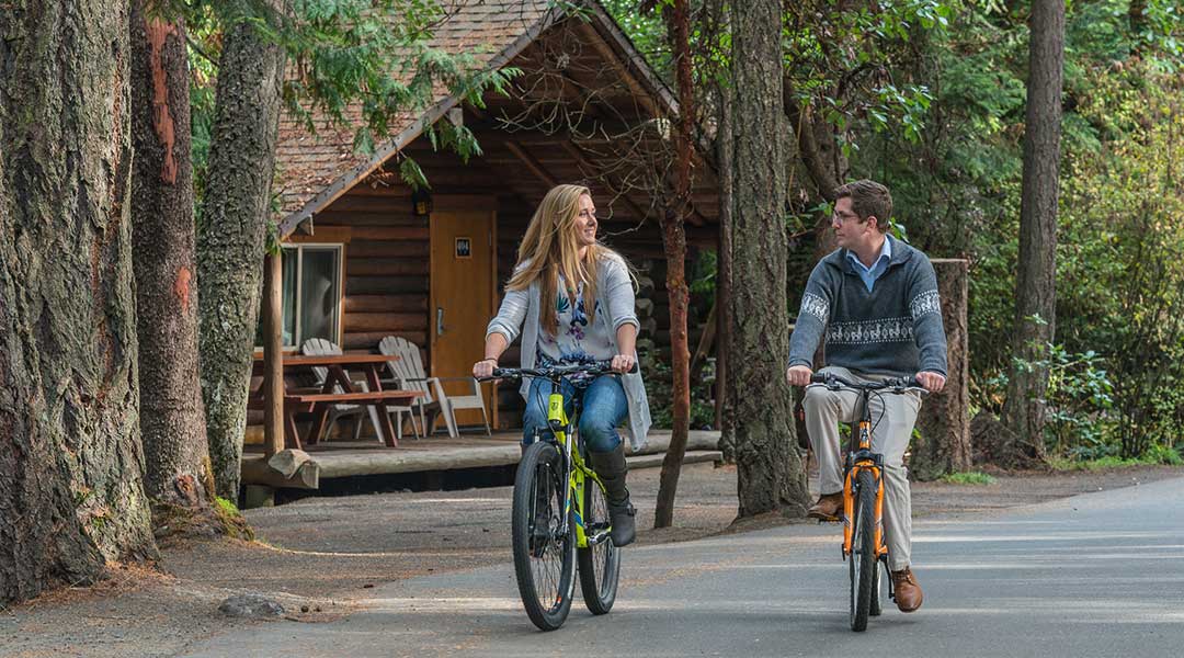 Couple biking side by side along path from cottage at Tigh Na Mara Resort and Spa in Parksville Couple biking side by side along path from cottage at Tigh Na Mara Resort and Spa in Parksville