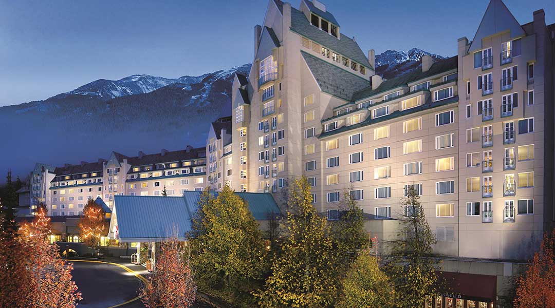 The exterior building of the Fairmont Chateau Whistler with some mountains at night