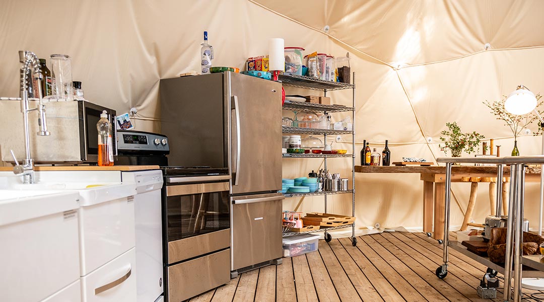 The kitchen area with stove and fridge inside the social dome at the Haida Gwaii Glamping Co The kitchen area with stove and fridge inside the social dome at the Haida Gwaii Glamping Co
