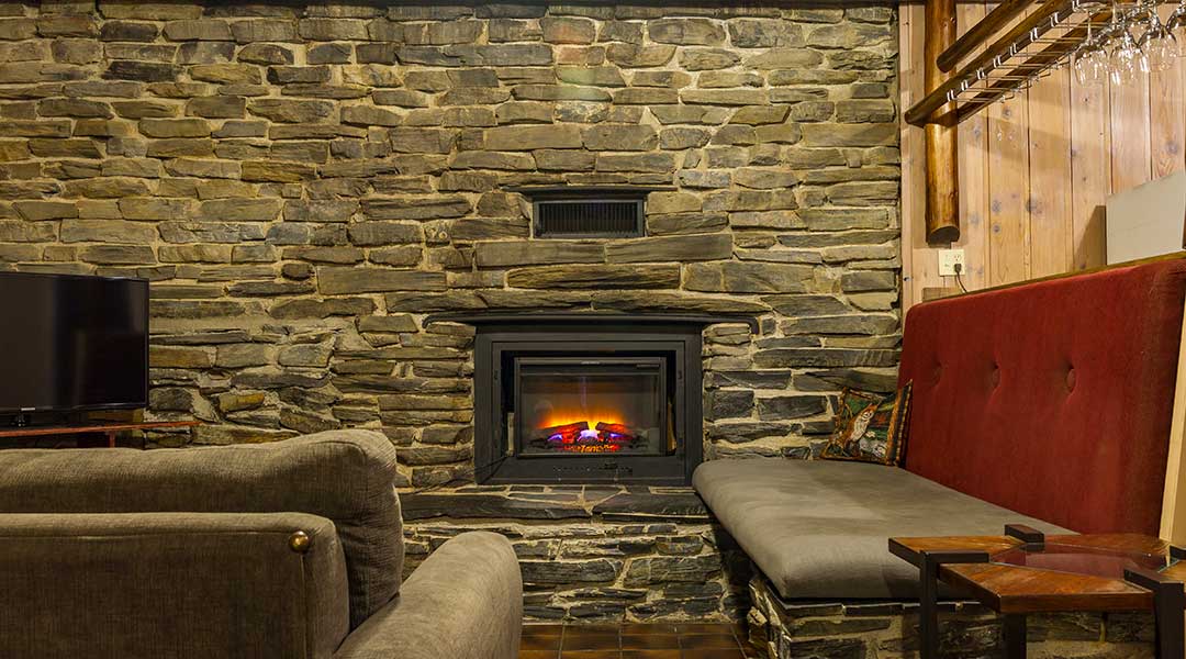 Fireplace in dark brick wall near sofa and TV in the lodge suite at the Bella Coola Mountain Lodge Fireplace in dark brick wall near sofa and TV in the lodge suite at the Bella Coola Mountain Lodge