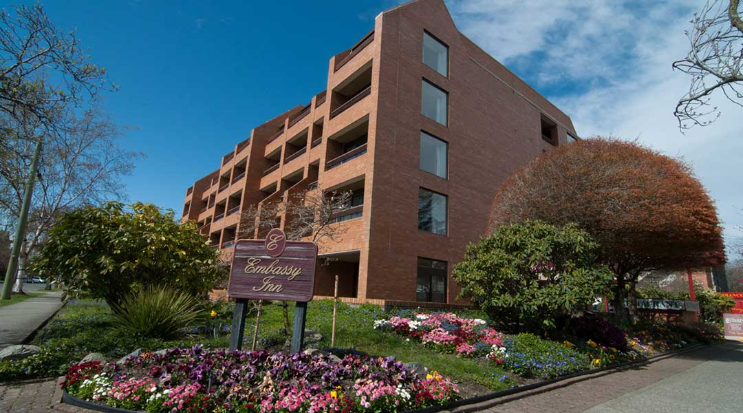 Garden and lawn in front of exterior of The Embassy Inn in Victoria BC
