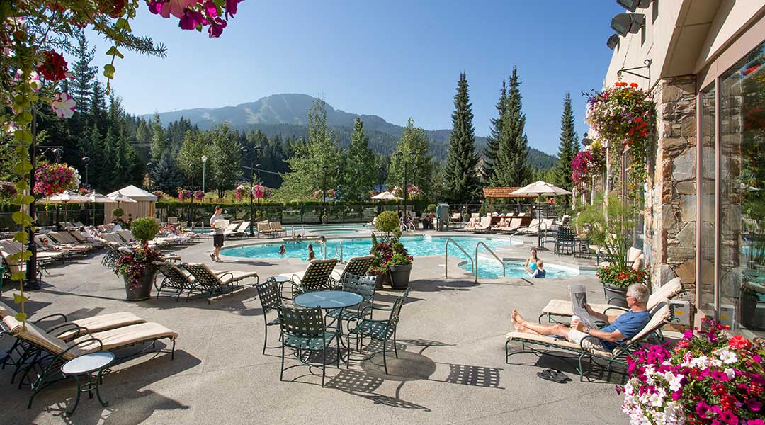 The outdoor pool terrace with people swimming and lounging at the Fairmont Chateau Whistler